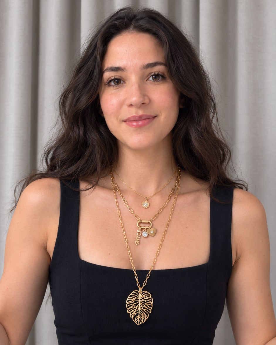 Woman wearing layered gold necklaces from EMESLY